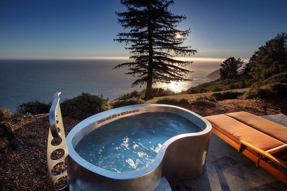Private outdoor hot tub set on a cliffside patio, overlooking the ocean and coastal landscape